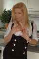 Pierced mature blonde Nina posing in a tight businessdress and stockings in front of the kitchen