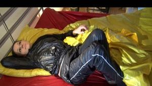 Lucy lolling in bed wearing a sexy black rainwear combination (Video)