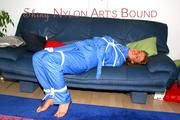 Katharina tied and gagged on a sofa wearing blue shiny downwear (Pics)
