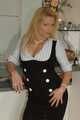 Pierced mature blonde Nina posing in a tight businessdress and stockings in front of the kitchen