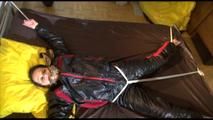 Liz tied and gagged on a bed wearing an oldschool black/red shiny nylon downwear combination (Video)