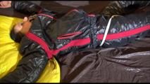 Liz tied and gagged on a bed wearing an oldschool black/red shiny nylon downwear combination (Video)