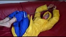 Sonja wearing a blue rain pants and a yellow PAMY down jacket while bonding herself an the sofa (Video)
