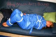 Katharina tied and gagged on a sofa wearing blue shiny downwear (Pics)