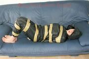 Katharina tied, gagged and hooded with tape on a sofa wearing sexy shiny nylon rainwear (Pics)