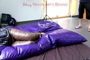 Samantha tied and gagged on bed wearing shiny downpants in brown and a black downjacket (Pics)