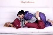 Sophie tied and gagged by Jill on a sofa wearing a shiny silver PVC sauna suit which is slitted by Jill (Pics)