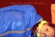 Mara tied and gagged on a sofa wearing a shiny black rain pants and a sexy lightblue down jacket (Video) 