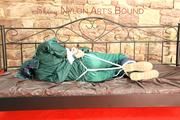 Pia tied, gagged and hooded in a princess bed wearing sexy shiny green rainwear (Pics)