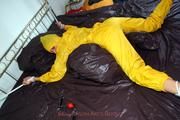 Stella tied and gagged in a shiny yellow rainsuit