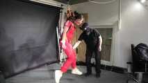 Marie in a custom video suspended in a shiny nylon Jumpsuit