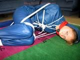 one of our archive girls tied and gagged in a shiny nylon rainsuit