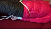 Mara tied and gagged on a sofa wearing a shiny pink down jacket and a black rain pants (Video)