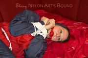 Lucy tied, gagged and hooded with ropes on a sofa wearing a sexy blue/red rainwear combination (Pics)