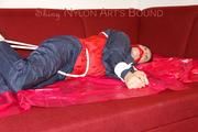 Lucy tied, gagged and hooded with ropes on a sofa wearing a sexy blue/red rainwear combination (Pics)