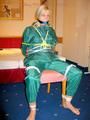 Blonde archive girl tied and gagged in an green shiny nylon rainsuit on a chair (Pics)
