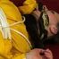 Lucy tied and gagged on a red sofa wearing a sexy yellow shiny nylon shorts and a yellow rain jacket (Video)
