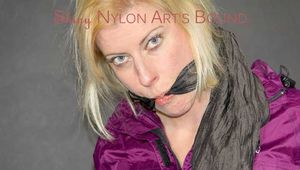 Pia tied and gagged on a bed with belts wearing a sexy black shiny nylon shorts and a purple shiny nylon rain jacket (Pics)