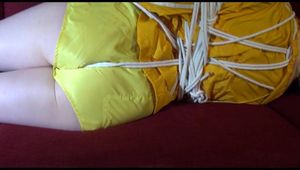 Lucy tied and gagged on a red sofa wearing a supersexy yellow shiny nylon shorts and a yelow rain jacket (Video)