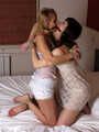 Gagged with a double ballgag, barefoot Dolly and Jessica, tied kneeling face to face, wiggles on the bed
