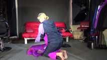 Watching Pia wearing a blue/purple/pink shiny nylon rain suit folding clothes and tidying up the studio (Video)