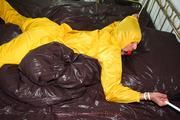 Stella tied and gagged in a shiny yellow rainsuit