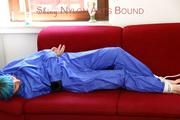 Mara tied and gagged on a red sofa wearing a sexy shiny lightblue rainwear (Pics)