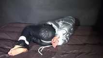 Watching sexy Sandra being tied and gagged on a bed with ropes and a ballgag wearing a supersexy shiny black nylon pants and a silver down jacket (Video)