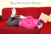 Mara tied and gagged on a red sofa wearing a sexy black rain pants and a shiny pink down jacket (Pics)