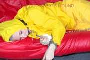 MARA ties, gagges and hoodes herself with cuffs and a ballgag on a sofa wearing sexy yellow rainwear (Pics)