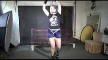 Mara wearing a sexy darkblue/purple shiny nylon shorts tied and gagged overhead with ropes and ballgag as well as a bar on the feet (Video)