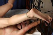 Ballgagged barefoot topless Cynthia in white panties, tied on the bed with her legs pulled up and tied wide-spread, is being played with vibrator by camera man