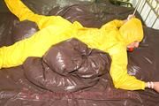 Stella tied and gagged on a bed wearing a supersexy yellow rainwear combination (Pics)