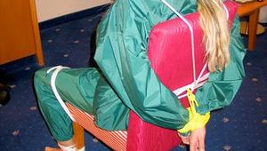 Blonde archive girl tied and gagged in an green shiny nylon rainsuit on a chair (Pics)