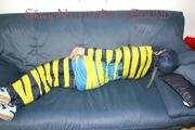 Katharina tied and gagged with tape on a sofa wearing shiny rainwear (Pics)