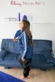 Katharina posing on a sofa wearing a blue/black shiny nylon rainwear (Pics)