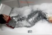 Simone in an shiny grey pvc sauna suit tied and gagged by Sophie in the bath tub (pics)