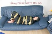 Katharina tied, gagged and hooded with tape on a sofa wearing sexy shiny nylon rainwear (Pics)