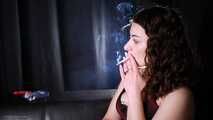 Dark-haired Russian girl smoking a cigarette on the studio couch