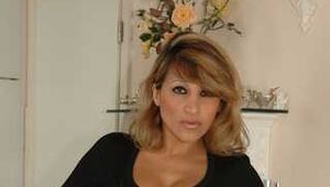 Busty Alexandra posing in a tight black top and a grey skirt at the counter