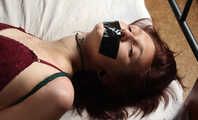 Tapegagged barefoot Kim in red panties and purple bra, hogtied with her elbows tightly tied together, wiggles and rolls on the bed