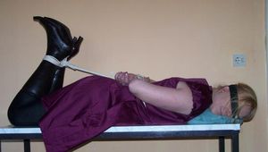 Hogtied im bordeauxfarbenen Kleid auf einem Tisch