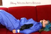 Mara tied and gagged on a red sofa wearing a sexy shiny lightblue rainwear (Pics)