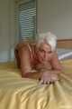 Short haired blonde MILF Claudia posing on bed