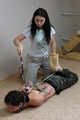 Hazel dominates Gregory, bit-gagged and hogtied with his hands in reverse prayer