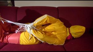 Lucy tied, gagged and hooded on a red sofa wearing a sexy orange shiny nylon pants and a yellow rain jacket (Video)