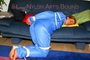 Katharina tied and gagged on a sofa wearing blue shiny downwear (Pics)