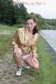 Watching out beautiful archive girl wearing a white shiny nylon shorts and a golden rain jacket posing outdoor (Pics)