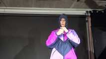 Watching Pia wearing a blue/purple/pink shiny nylon rain suit folding clothes and tidying up the studio (Video)