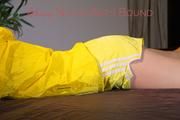 Lucy tied and gagged on bedposts face-down position wearing a sexy yellow shiny nylon shorts and a yellow rain jacket (Pics)